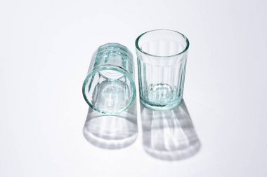 close up view of empty glasses and shadows on white surface