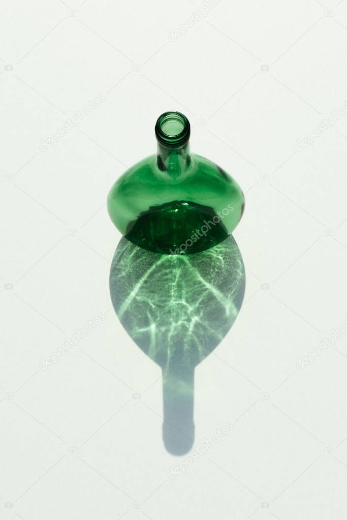 close up view of empty glass bottle with reflection on white tabletop