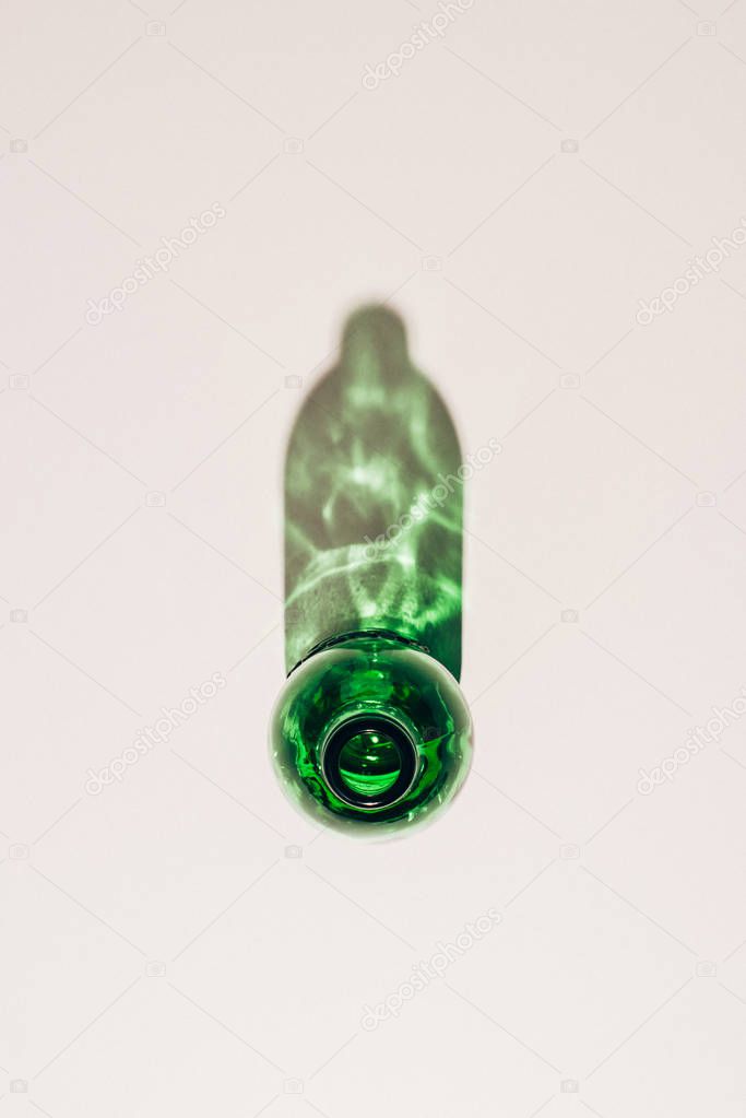top view of empty green glass bottle with shadow on white tabletop