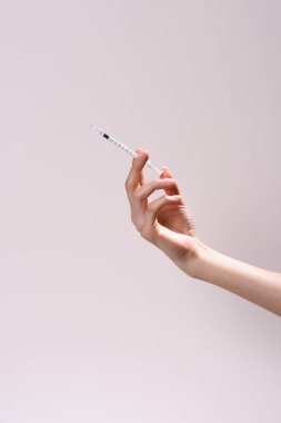 cropped shot of woman holding syringe isolated on grey
