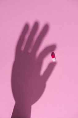 ilaç kapsül pembe yüzeyde tutan el gölge Üstten Görünüm