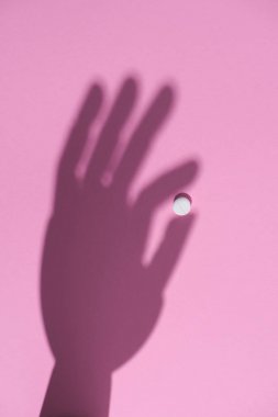 Beyaz hap pembe yüzeyde tutan el gölge Üstten Görünüm