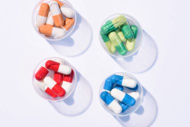 top view of various colorful pills in plastic cans on white