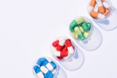 top view of various colorful pills in plastic bowls in row on white clipart