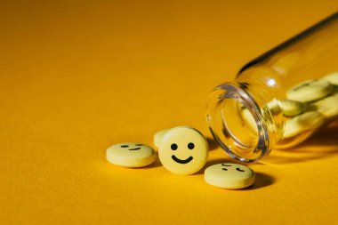 close-up shot of pills with smiley faces and glass bottle on yellow clipart