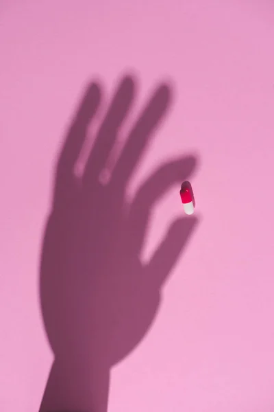 Vista Superior Sombra Mão Segurando Cápsula Droga Superfície Rosa — Fotografia de Stock