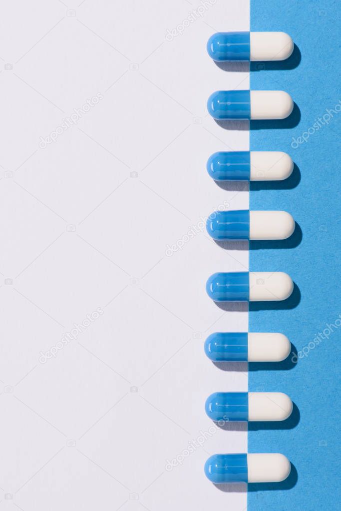 top view of row of drug capsules on halved white and blue surface