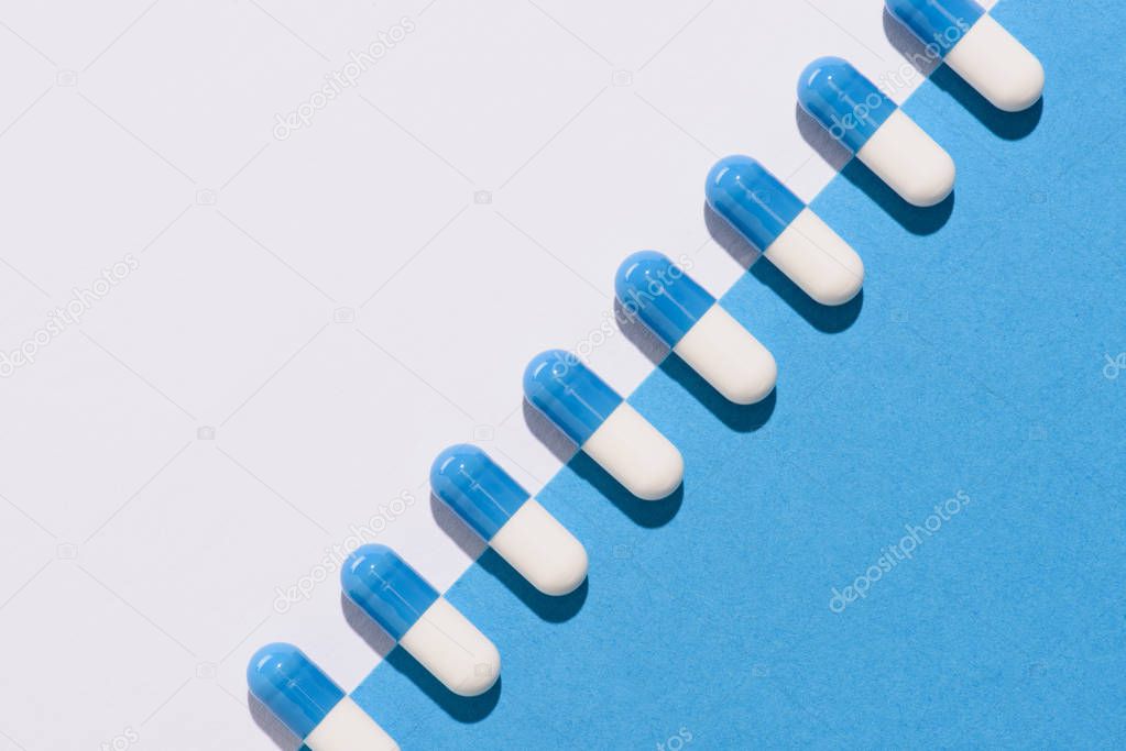 top view of row of pills on halved white and blue surface