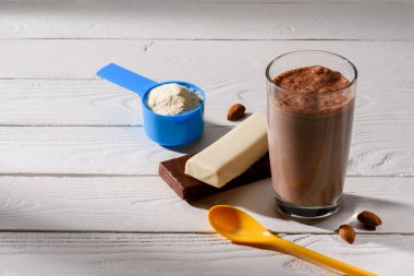 cam bir protein sallamak Beyaz ahşap masa üzerinde enerji barlar