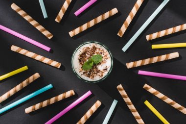 Çikolata talaşı ve tatlı ve içme pipetleri tarafından çevrili nane ile milkshake Üstten Görünüm 