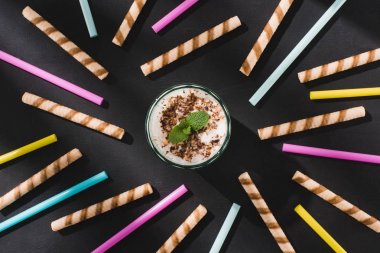top view of milkshake with chocolate shavings and mint surrounded by sweet and drinking straws  clipart