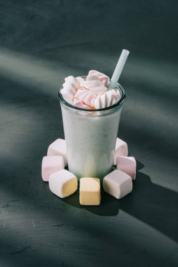 closeup shot of marshmallows, milkshake glass with drinking straw on table clipart
