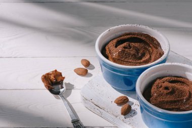 bowls with tasty chocolate dessert with cocoa powder on wooden table clipart