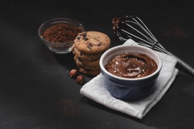 bowl with chocolate dessert, cocoa powder, whisk and cookies on tabletop clipart