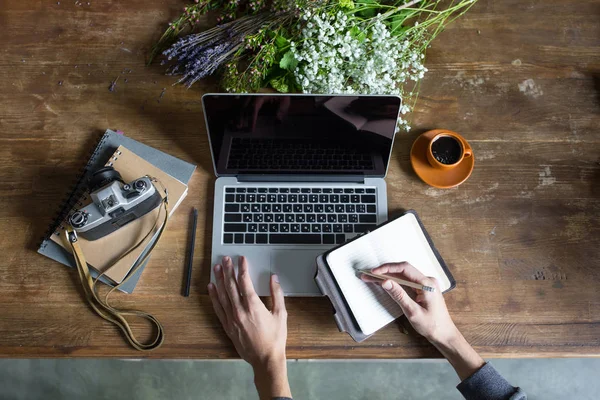 Person using laptop and graphic tablet at workspace with notebooks and vintage camera — Stock Photo