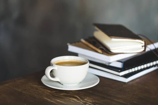 Nahaufnahme von Tasse Kaffee und Notizbüchern auf hölzerner Tischplatte — Stockfoto