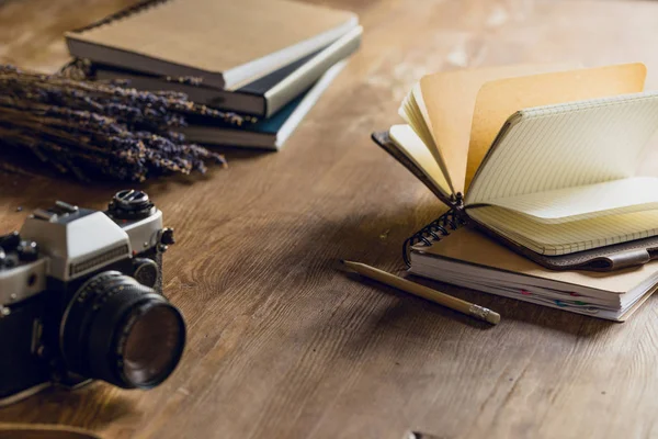 Close-up view of camera, dried flowers and notepads on wooden table — Stock Photo