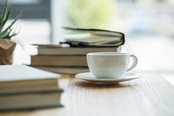 Nahaufnahme von Tasse Kaffee und Notizbüchern auf hölzerner Tischplatte — Stockfoto