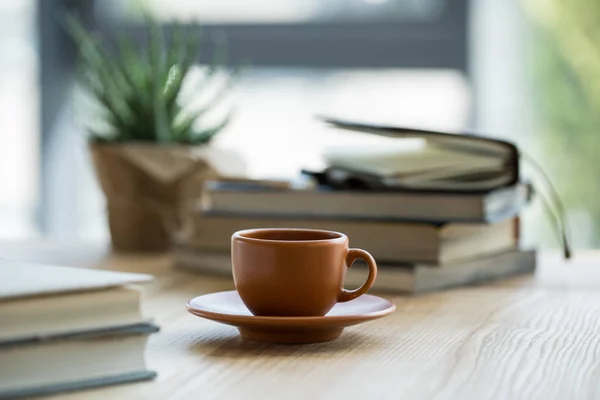 Vista de close-up da xícara de café e cadernos no tampo da mesa de madeira — Fotografia de Stock