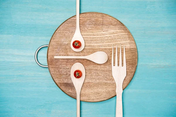 Vista superior de utensilios de cocina de madera con tomates en forma de cara en el tablero de la cocina - foto de stock