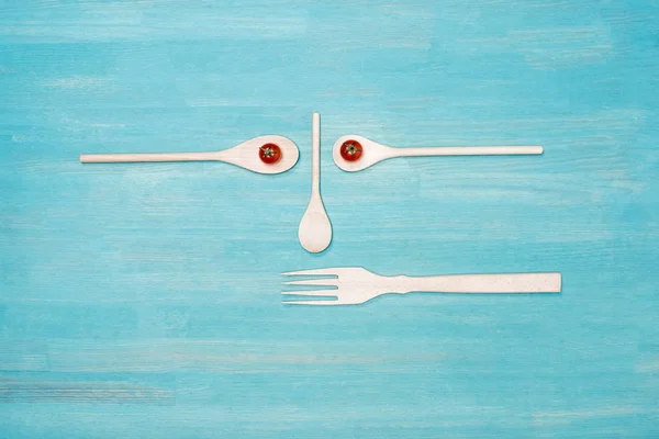 Draufsicht auf hölzerne Küchenutensilien mit Kirschtomaten auf blauer Tischplatte — Stockfoto