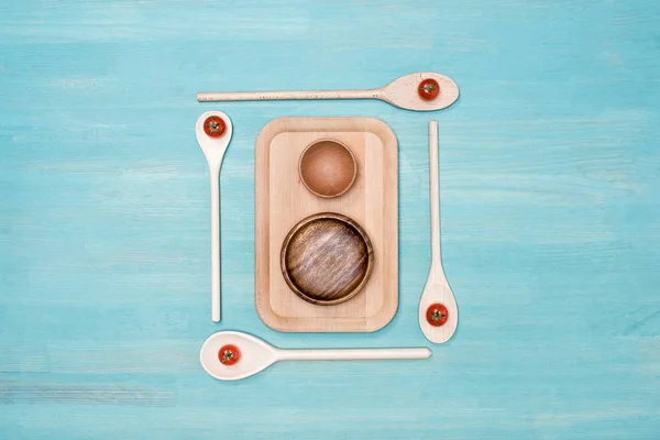 Top view of wooden cutting board with kitchen utensils and cherry tomatoes on table — Stock Photo