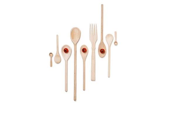Top view of various wooden cooking utensils with cherry tomatoes isolated on white — Stock Photo