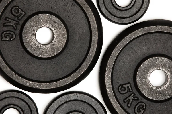 Vista de cerca de diferentes placas de peso para el entrenamiento con pesas aisladas en blanco - foto de stock