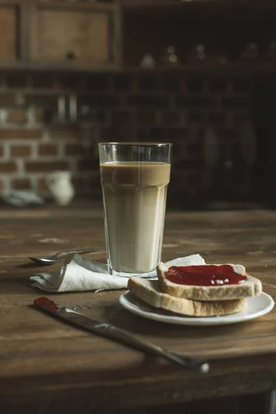 Latte und Brot mit Marmelade auf Holztischplatte — Stockfoto