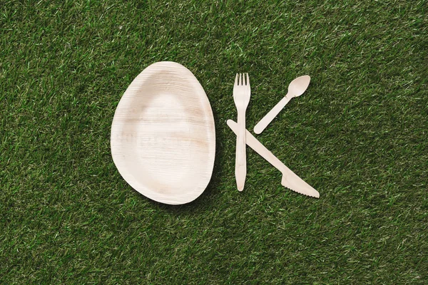Couverts en bois et assiette sur herbe — Photo de stock