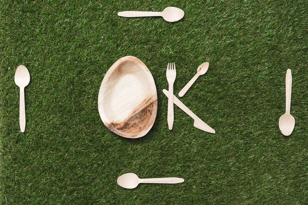 Posate in legno e piatto su erba — Foto stock