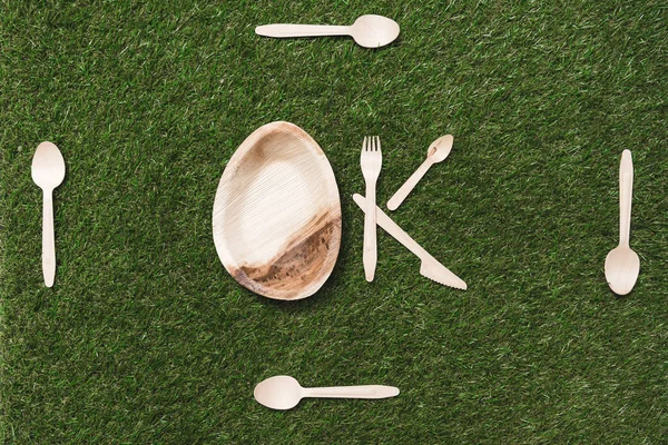 Wooden cutlery items and plate on grass — Stock Photo