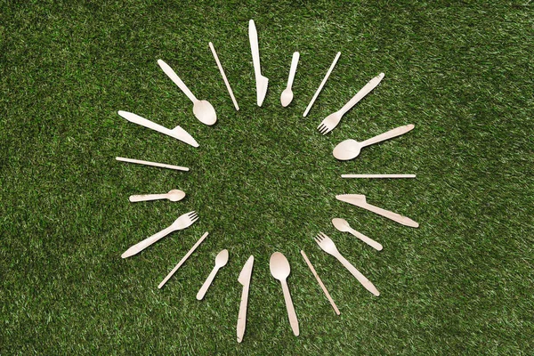 Wooden spoons with forks and knives on grass — Stock Photo
