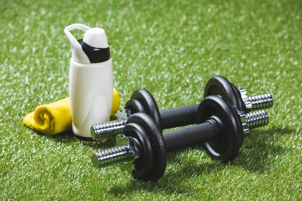 Hanteln und Wasserflasche mit Handtuch auf Gras — Stockfoto