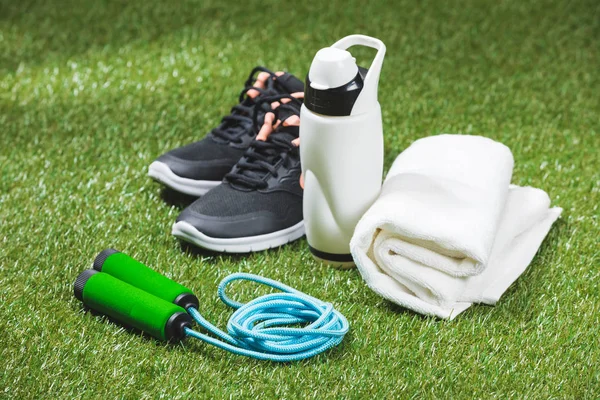 Turnschuhe mit Wasserflasche und Handtuch auf Gras — Stockfoto