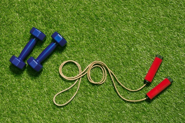 Dumbbells with jump rope on grass — Stock Photo