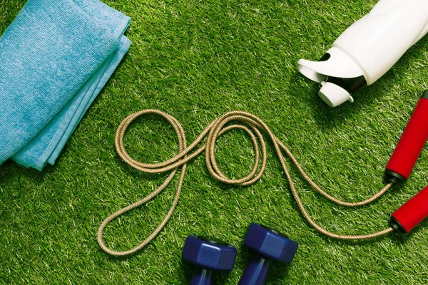 Cuerda de salto con toalla y botella en la hierba — Stock Photo