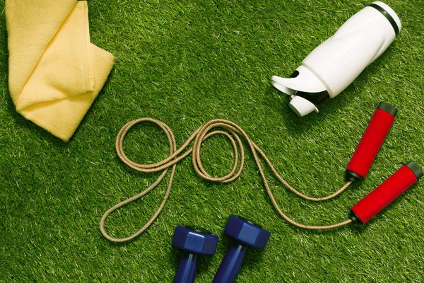 Pular corda com toalha e garrafa na grama — Fotografia de Stock