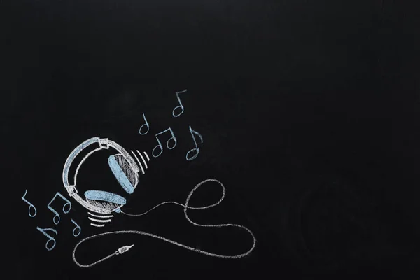 Headphones with musical notes drawn on chalkboard — Stock Photo