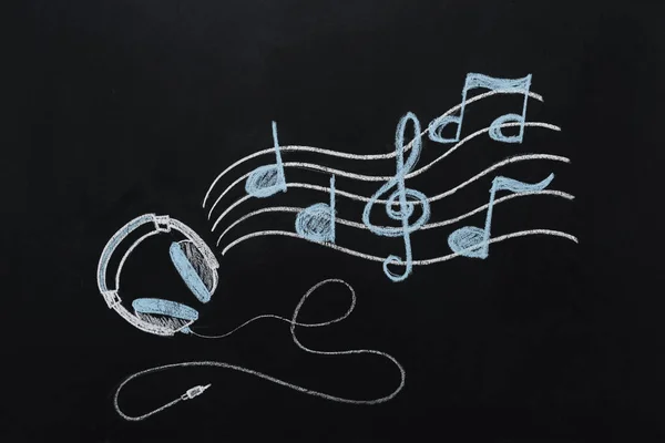 Auriculares con notas musicales dibujadas sobre pizarra — Stock Photo