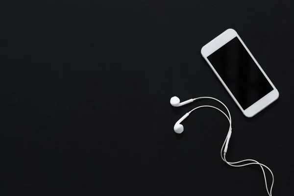 Smartphone con pantalla en blanco y auriculares - foto de stock