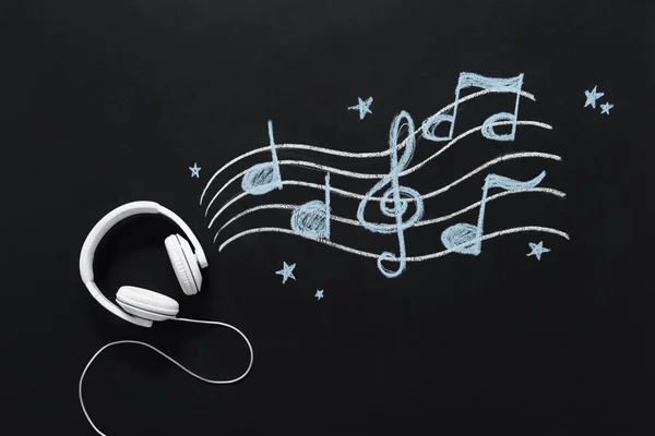 Headphones with musical notes drawn on chalkboard — Stock Photo