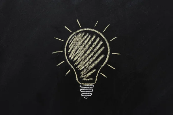 Electric bulb drawn on black chalkboard — Stock Photo