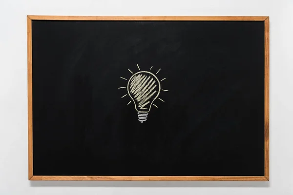 Электрическая лампочка нарисованная на черной доске — стоковое фото