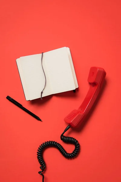 Telephone handset and blank notebook — Stock Photo