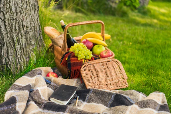 Cesto da picnic e taccuino su plaid — Foto stock