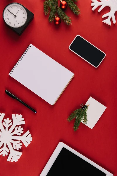 Piso con suministros de oficina, copo de nieve decorativo y juguetes de Navidad aislados en rojo - foto de stock