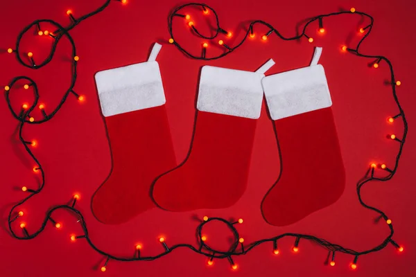 Flat lay with arranged empty christmas socks and lights isolate don red — Stock Photo