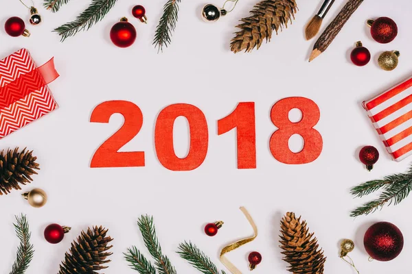 Flache Liege mit arrangierten Tannenzapfen, verpackten Geschenken, Weihnachtsspielzeug und Jahresschild 2018 isoliert auf weiß — Stockfoto