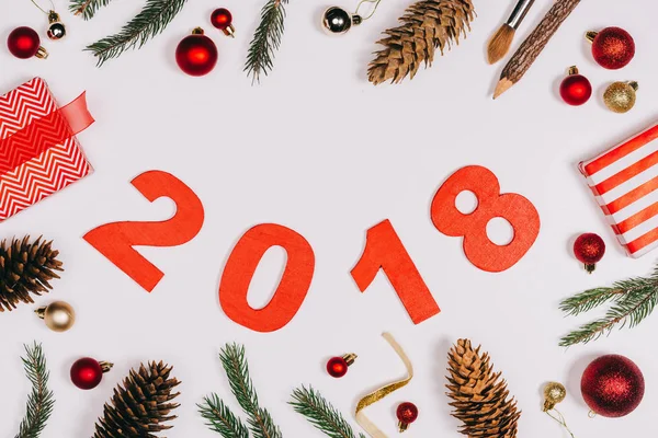 Pose plate avec des cônes de pin arrangés, cadeaux enveloppés, jouets de Noël et 2018 panneau d'année isolé sur blanc — Photo de stock